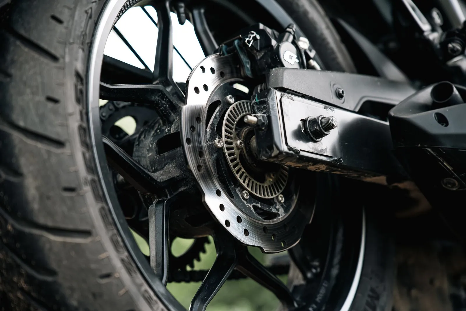 Detailed view of a motorcycle's rear wheel, showcasing the disc brake and tire in sharp focus.